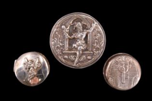 Three silver and white metal pill boxes, variously decorated with a jester, a fairy and a sphynx,