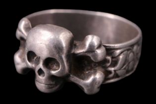 An early 20th Century Russian white metal ring, being a floral relief band faced with a skull and