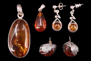 Four items of late 20th Century amber and white metal jewellery, comprising a sun-spangled pendant