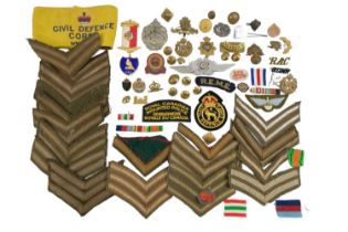 A quantity of military cap and other badges, a medallion, locket etc