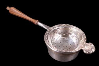 A late 20th Century silver tea strainer and stand, the strainer having an applied shell motif and