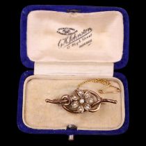 A cased Edwardian pearl brooch, being a pearl-set flowerheard set on a open knotted bar, marked '