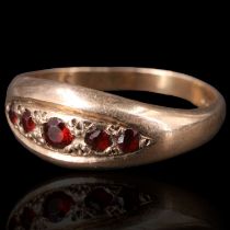 A garnet and 9 ct gold ring, comprising five graded round-cut stones, gypsy-set on the lens-shaped