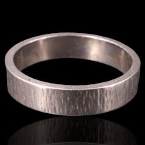An 18 ct white gold wedding band of rectangular section with a bark textured finish, London, 1977,