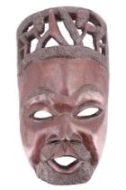 A carved African mask, the hair framing two crouching figures, 20th Century, 34 cm x 60 cm