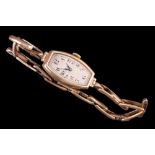 A 1920s 9ct gold wristlet watch having a crown-wound movement, elongated tonneau face, blued steel