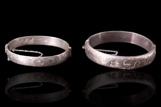 A foliate-engraved silver hinged bangle together with one other, similar, 62 mm x 53 mm and 60 mm