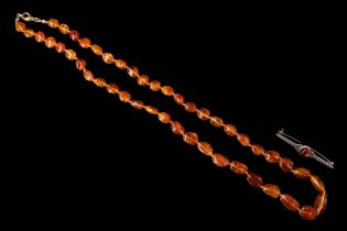 An amber matinee length necklace of subtly graduated polished beads, most being sun-spangled,