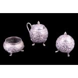 An Asian white metal three-piece condiment set, each element of spheroidal form and profusely