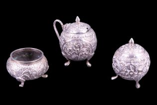 An Asian white metal three-piece condiment set, each element of spheroidal form and profusely