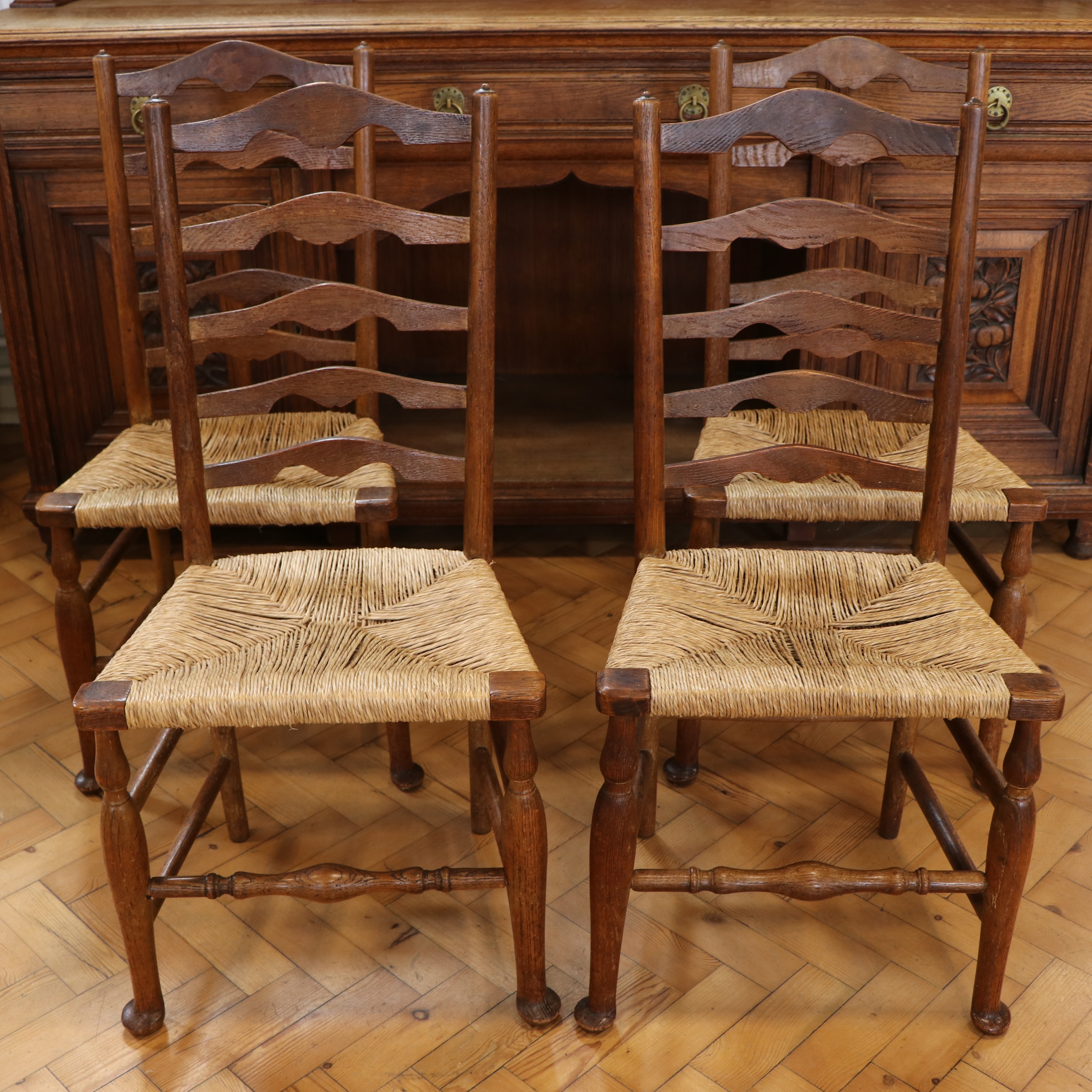 Four late 19th / early 20th Century rush-seated oak ladder-back chairs, 95 cm