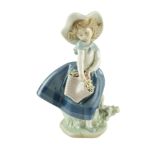 A Lladro figurine of a young girl holding a basket of flowers, late 20th Century, height 18 cm