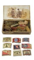 A collection of early 20th Century matchbox labels in a cigar box