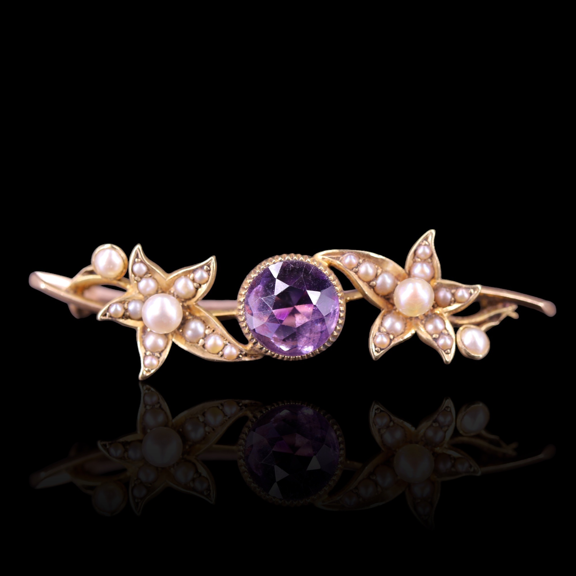 An antique amethyst, seed pearl and 15 ct gold brooch, comprising a central round-cut amethyst of