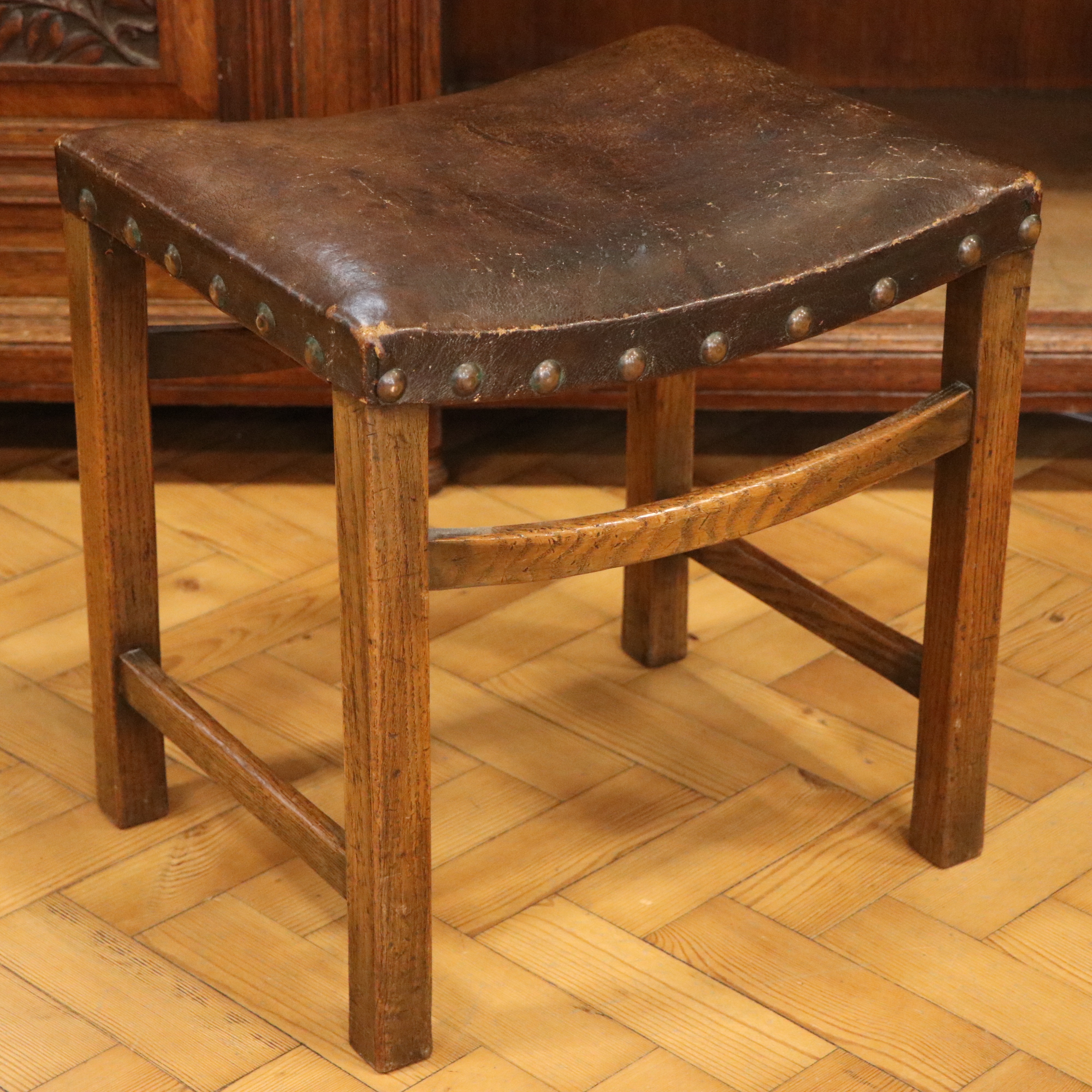 A George V oak dressing table stool, having a period leatherette-upholstered saddle seat with