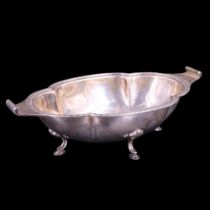 A 1930s silver dish, of cusped oval form with volute lug handles, having a dentil-and-bead-cluster