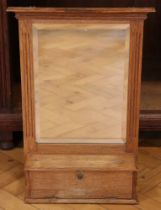 A late 19th / early 20th Century oak wall mirror cum shelf with integral small fall-front cabinet,