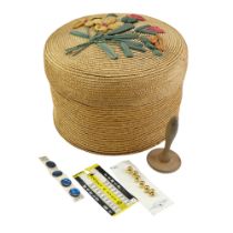 A vintage straw sewing basket with sewing accoutrements including a darning mushroom, buttons,