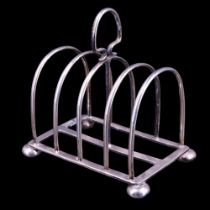 A George V silver four-slice toast rack, having slender arched divisions and standing on bun feet,