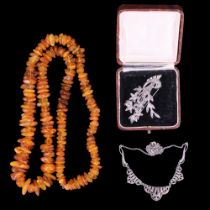 An inter-War European marcasite bead necklace, a floral brooch and an amber irregular bead necklace,