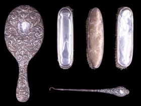 A silver-handled button hook together with a pair of silver-backed hair brushes and a hand mirror