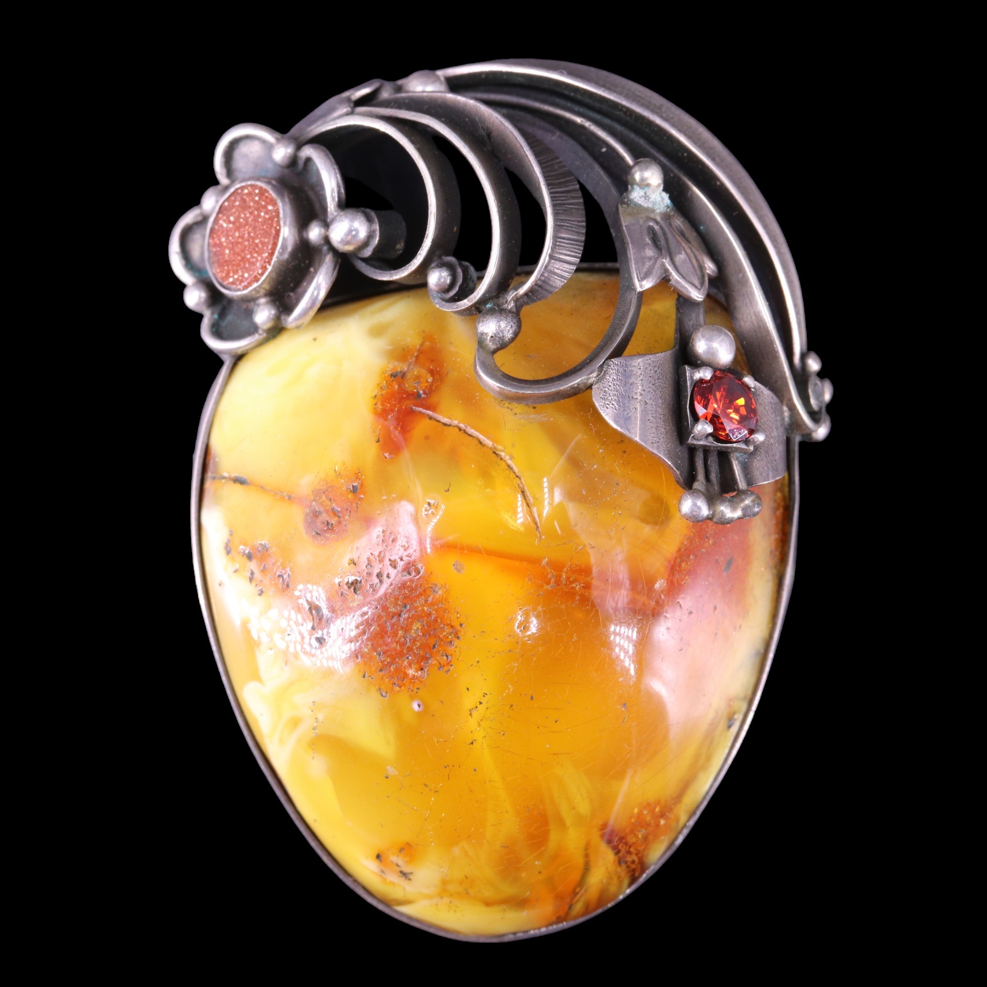 A large amber nodule brooch, bezel-set together with a small goldstone plaque and a facet-cut