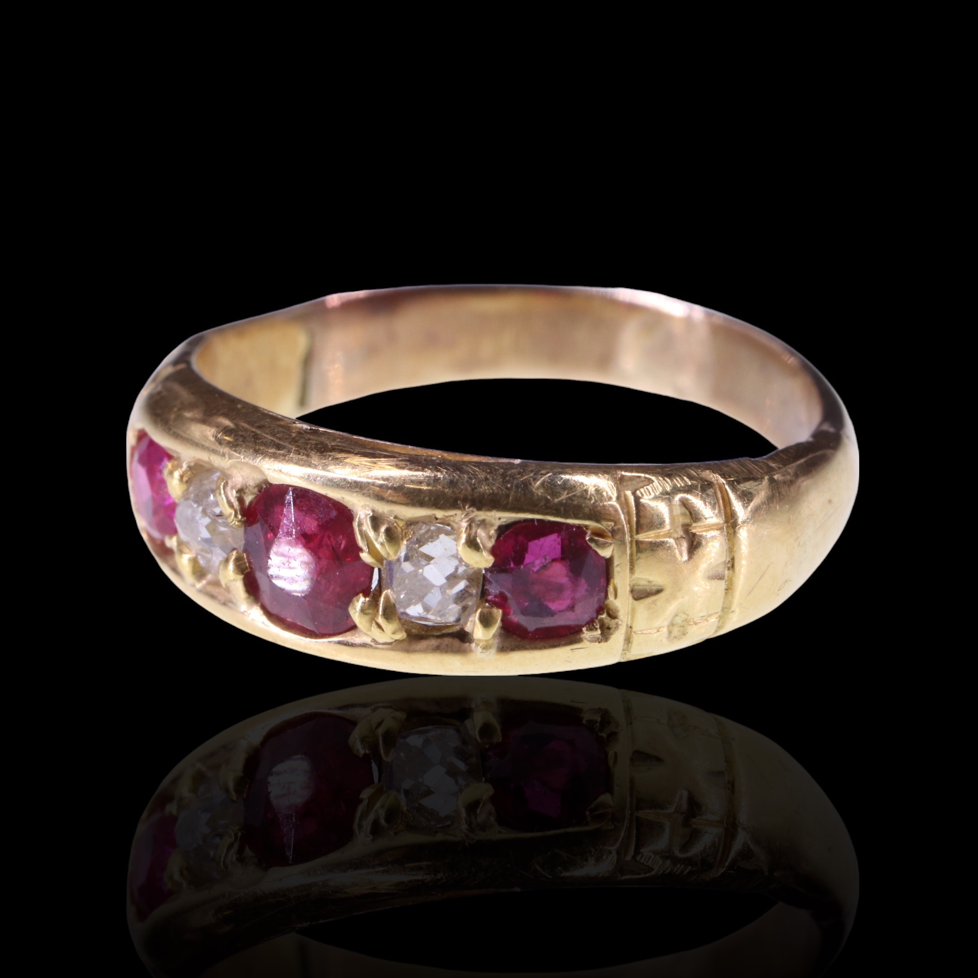 An antique ruby and diamond ring, comprising three round-cut rubies, the central stone of approx 0.3
