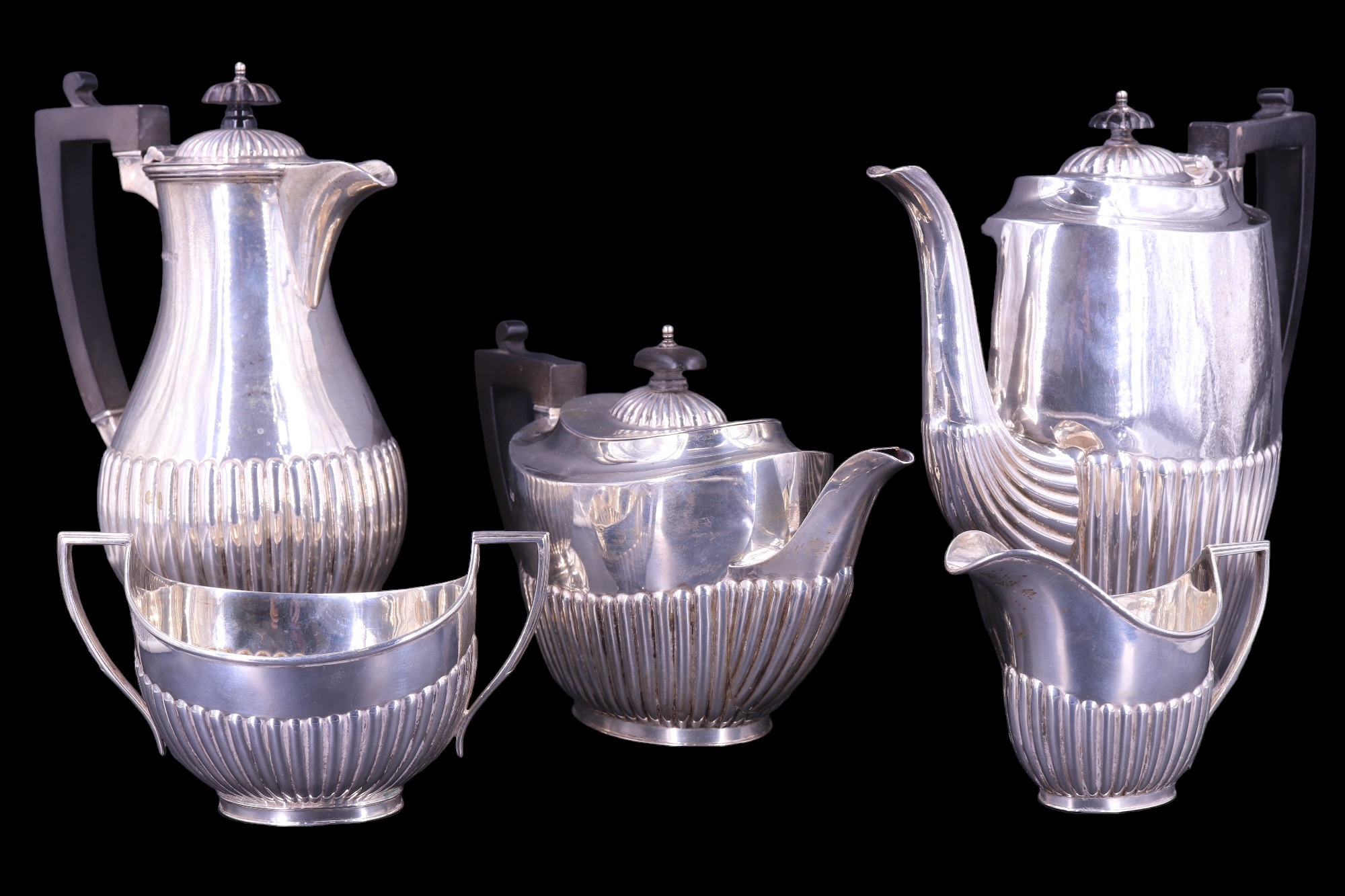 An early 20th Century silver four-piece tea service, in a Georgian gadrooned pattern with ebony