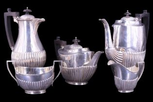 An early 20th Century silver four-piece tea service, in a Georgian gadrooned pattern with ebony