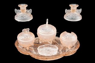 An Art Deco Sowerby pressed and frosted pink glass dressing table set, relief decorated in depiction