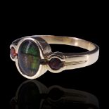 A three-stone ammolite ring, comprising a central oval cabochon bezel-set between two smaller