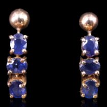 A pair of articulated sapphire and yellow metal drop earrings, each being a trio of claw-set oval