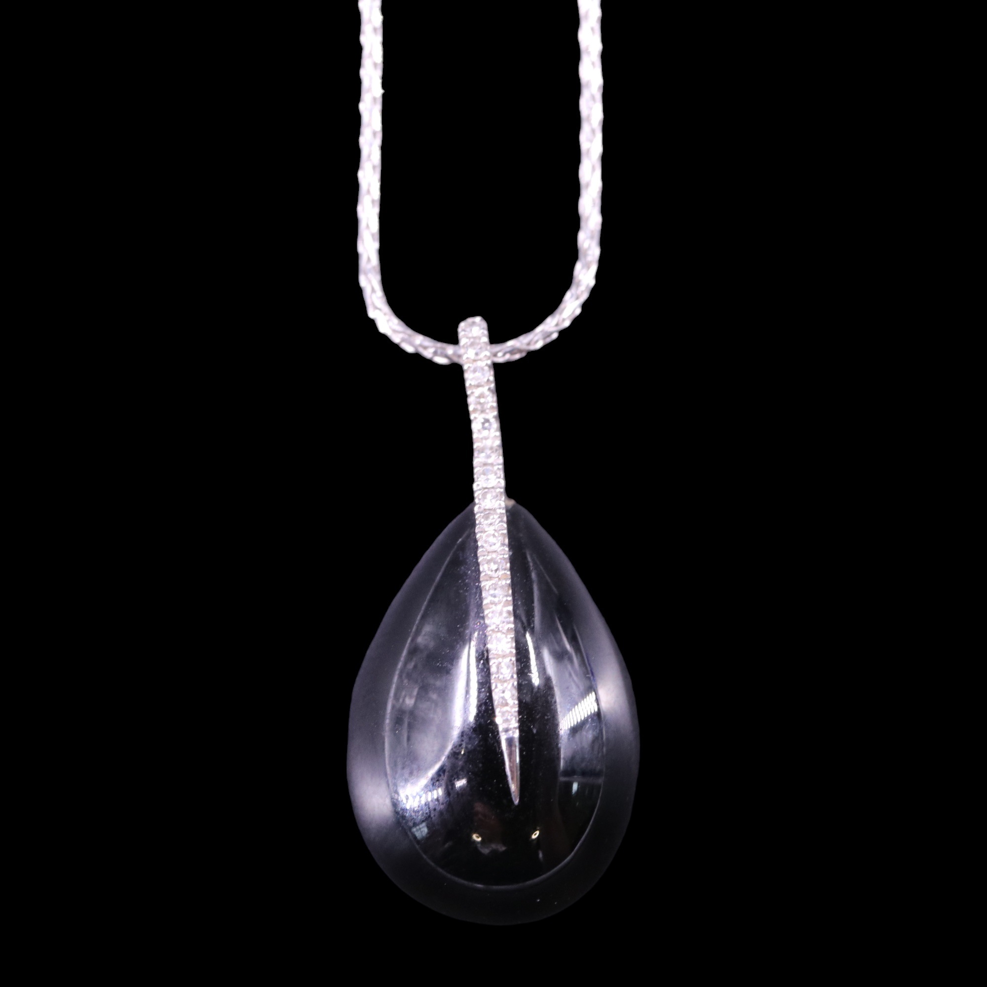 A contemporary black jadeite pendant, being a teardrop cabochon with fine, highly acute diamond-