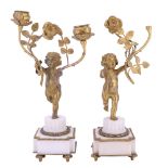 A pair of Louis XVI style gilt metal and alabaster figural candelabra, each in the form of a cupid