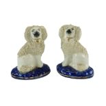 A pair of Victorian Staffordshire encrusted poodles on cushions, 14 cm