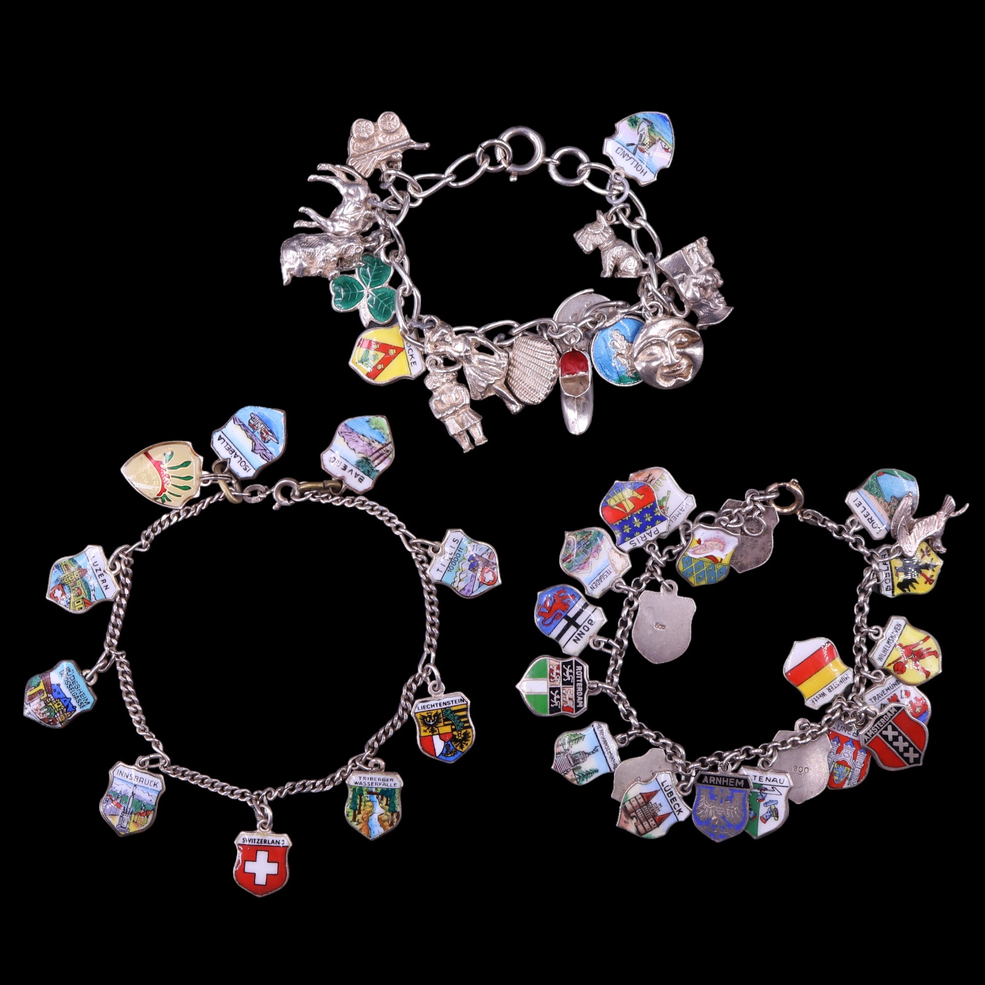 Three vintage white metal charm bracelets including European enamelled shield charms, 79 g