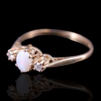 An opal and diamond ring, comprising an oval opal cabochon claw-set between a pair of small