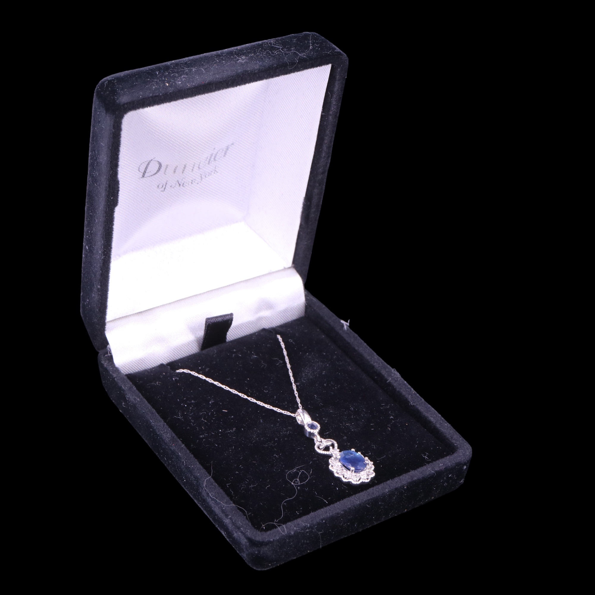 A contemporary articulated diamond and sapphire cluster pendant and chain comprising an oval-cut
