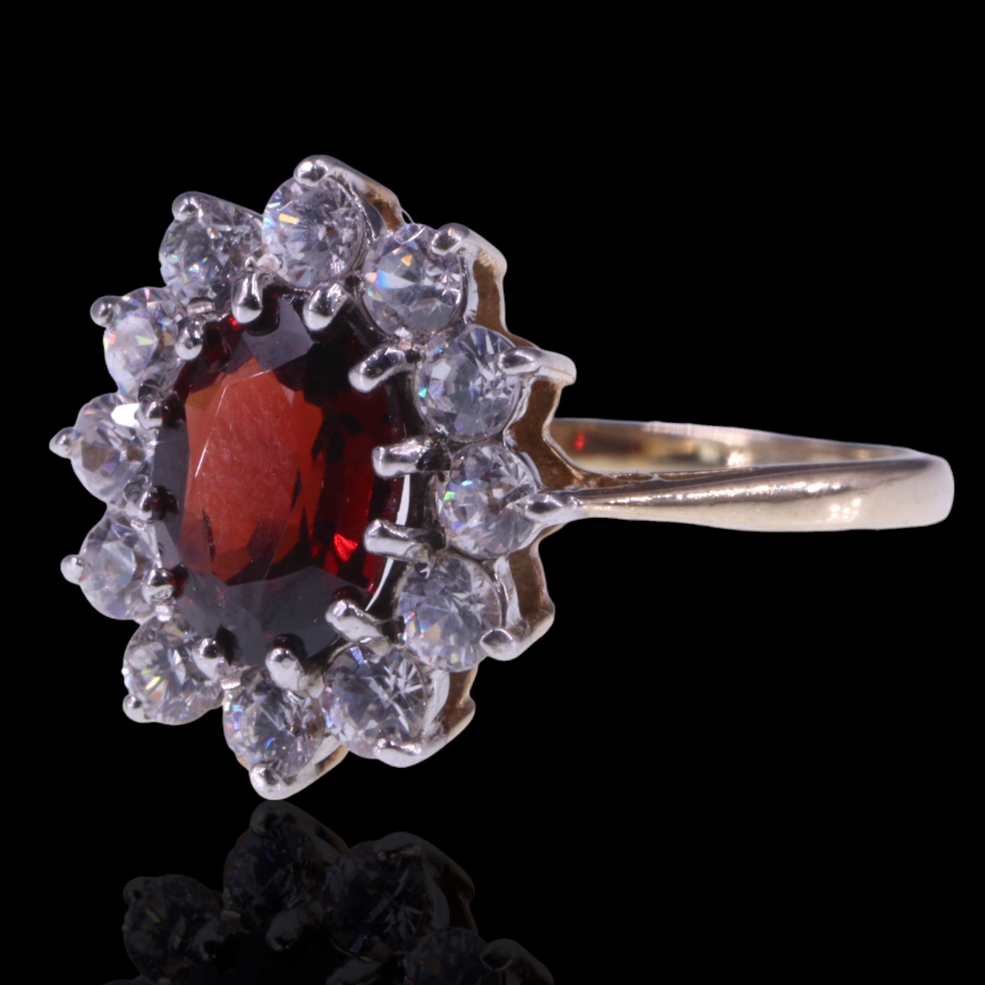 A 1980s garnet and white stone cluster ring, the central oval-cut garnet of approx. 1.4 cts, claw-