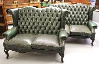 Pair of 20th Century green button leather upholstered wing back two seater sofas, with loose