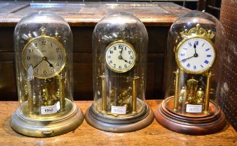 Group of three early to mid 20th Century brass anniversary clocks under glass domes