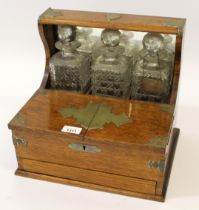Early 20th Century oak and brass mounted tantalus with three hobnail cut decanters, the base with