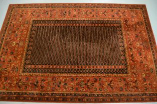 Machine woven Persian design carpet with a rectangular centre panel and dark ground with wide floral