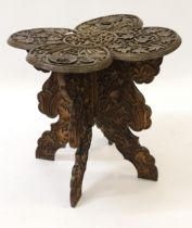 Heavily carved Eastern hardwood shaped top occasional table of foliate design on folding base (top