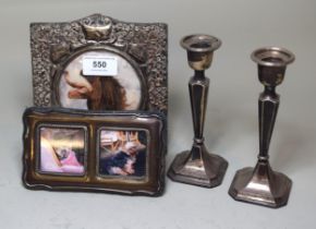 Pair of small silver candlesticks, silver mounted photo frame and a similar smaller twin frame