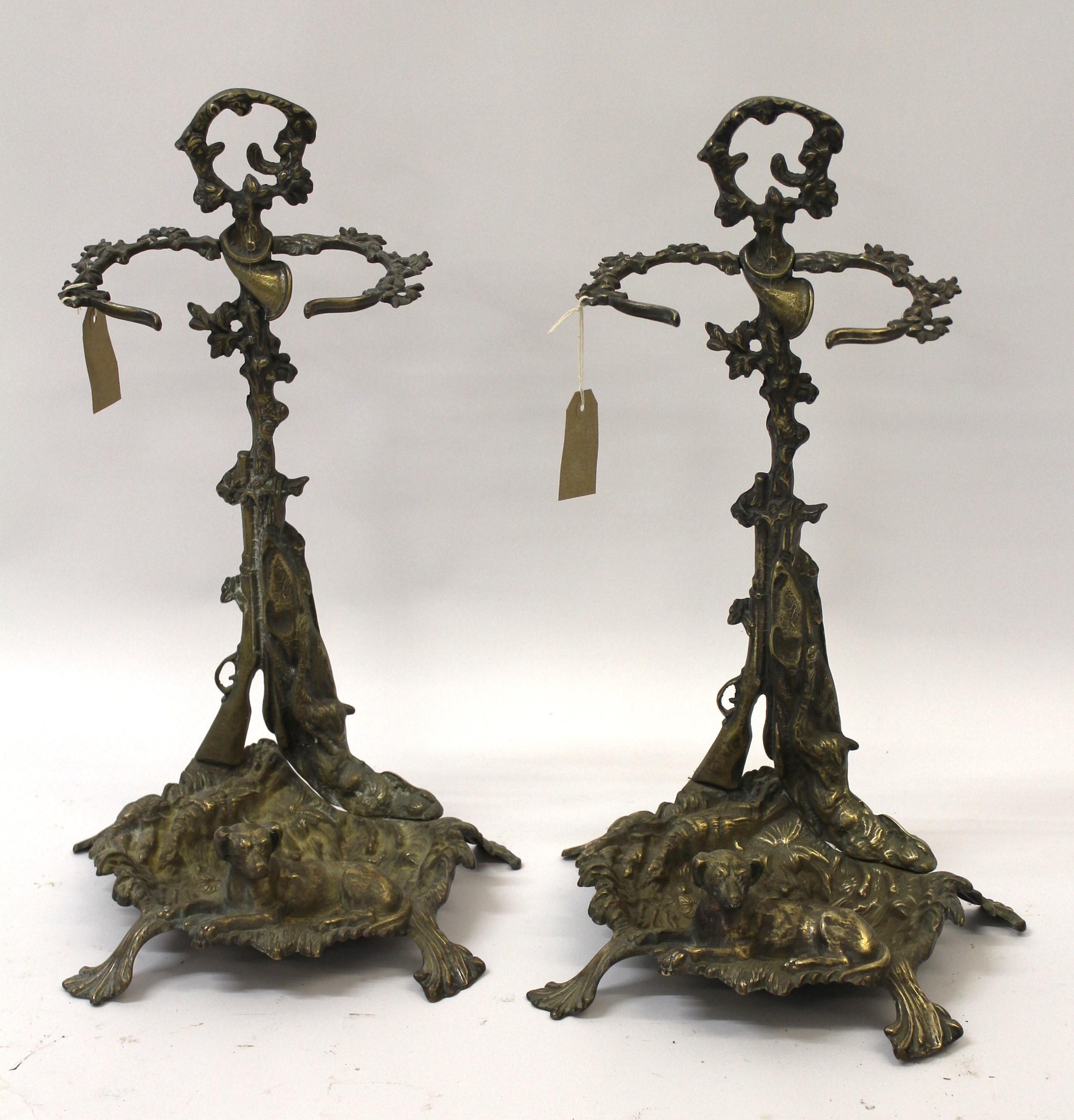 Pair of ornate brass stick stands mounted with figures of dogs, 56cm high