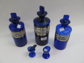 Group of three Bristol blue glass chemists jars with original labels, two similar eye baths and a