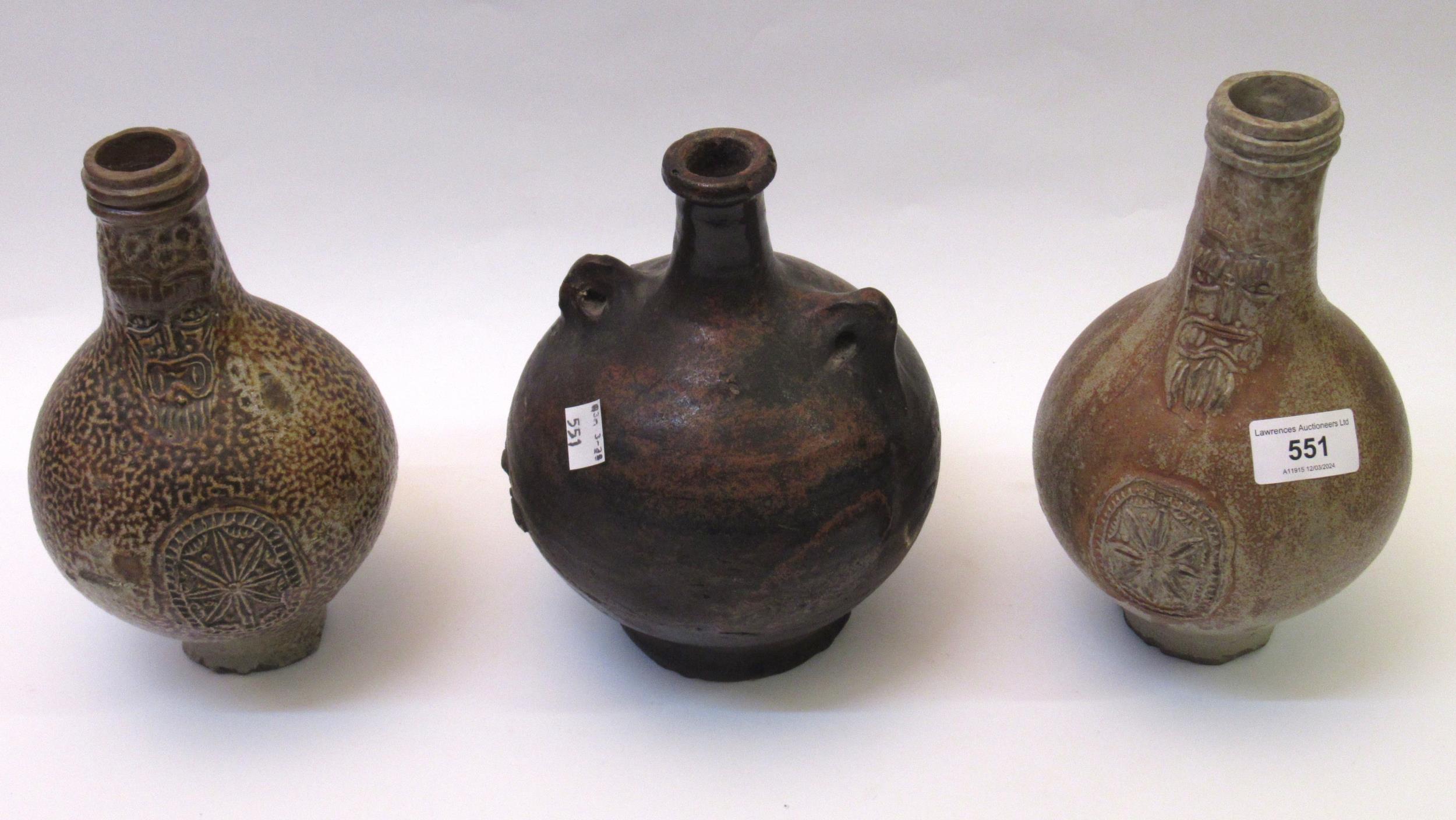 Two German stoneware mask head Bellarmine jugs, together with a terracotta bottle (all restored)