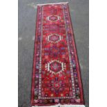 Small Karaja runner with a repeating hooked medallion design on a red ground with borders, 190 x
