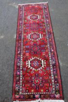 Small Karaja runner with a repeating hooked medallion design on a red ground with borders, 190 x